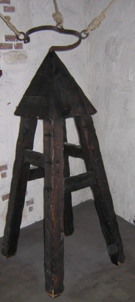 Abbildung eines historischen Folterinstruments („Judaswiege“) mit spitzer, pyramidenförmiger Sitzfläche zur Zufügung von Schmerzen